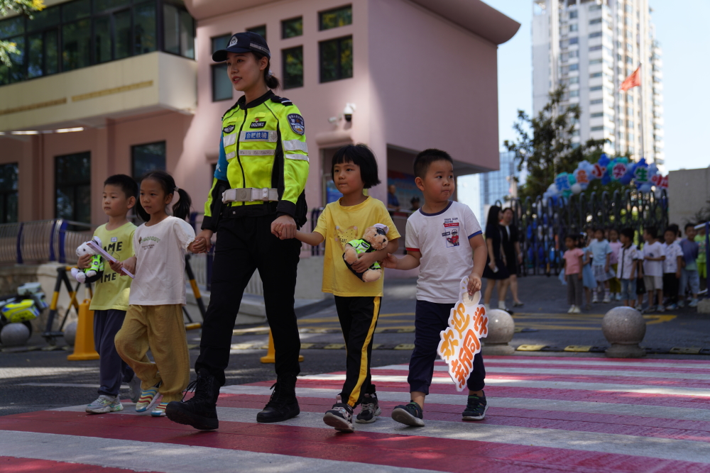 图为彩色斑马线上，一位交警带着新入学的孩子们进行交通情景模拟。9月1日上午，合肥市交警支队蜀山大队走进合肥市西园新村小学北校教育集团梅园校区，向一年级新生宣传文明交通安全知识，通过交通标识辨别、交通情景模拟等活动，提醒孩子们注意安全，珍惜生命。.JPG